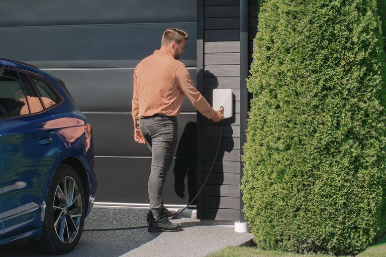 persona cargando coche eléctrico en casa